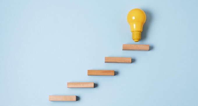 A single yellow light bulb on top of wooden blocks.