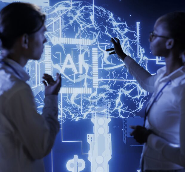 Two people discussing in front of a digital display with a brain and an AI character.