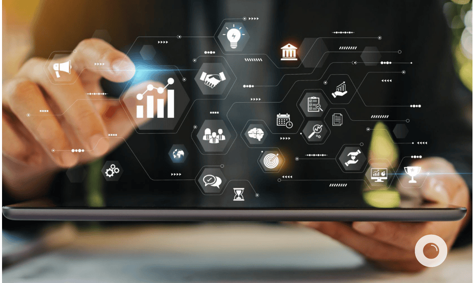 Hands of a person interacting with a tablet displaying a network of interconnected business symbols.