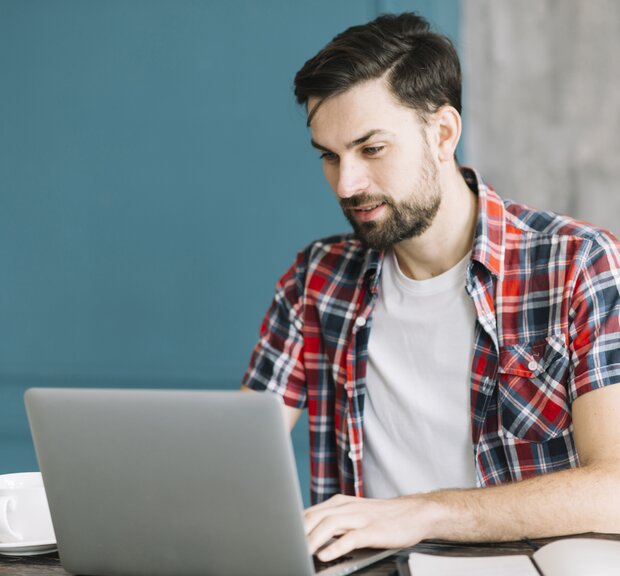 IT System Administrator, sits at a table working on his laptop