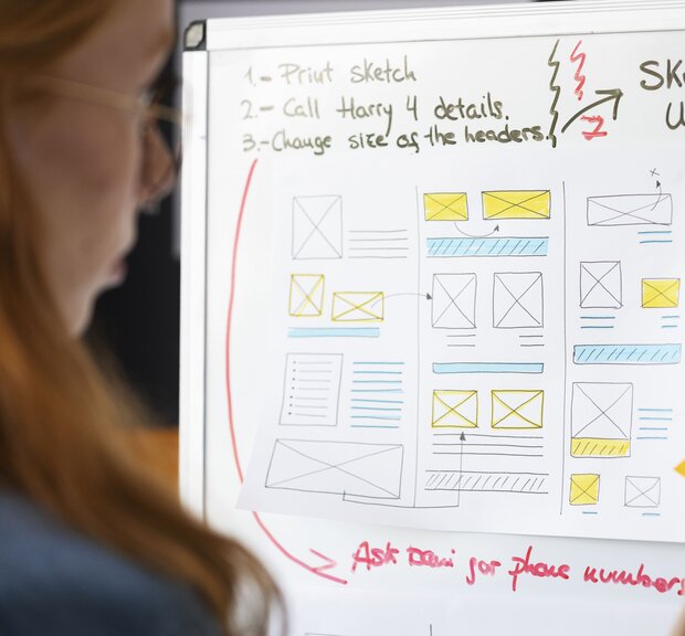 A woman, UX designer, notes down her concepts on a white whiteboard with a pen